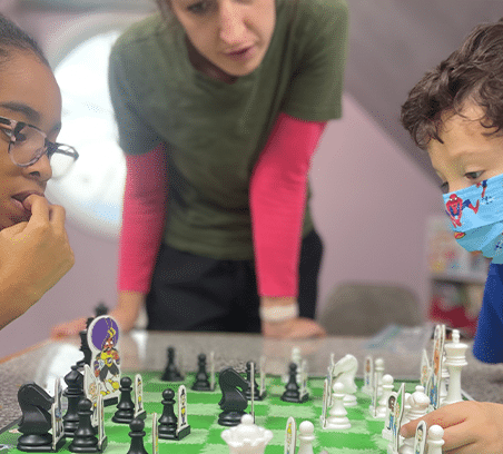 Kids strategizing at Chess Club with their teacher at Clairmont Advanced Education Center